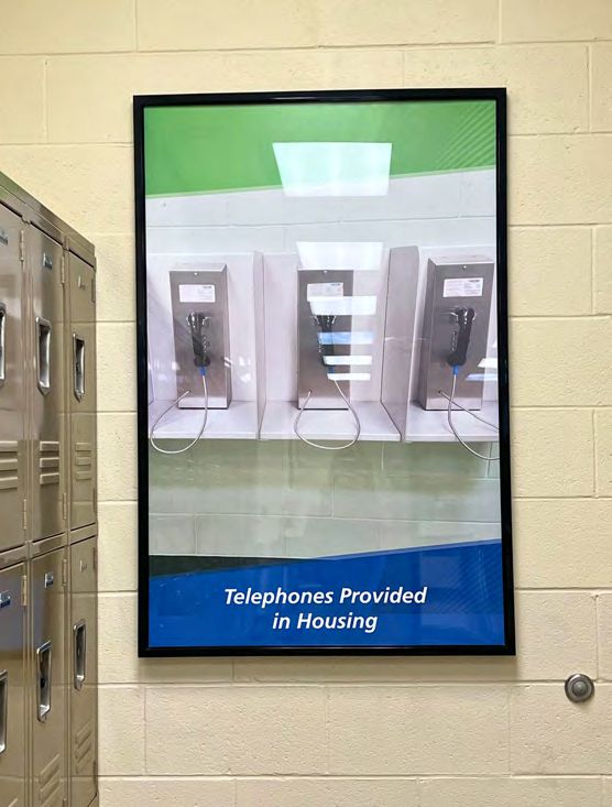Poster showing image of 3 mounted telephones on shelves with thin partition between them above text that states, 'Telephones Provided in Housing'.
